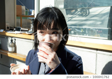 Woman drinking a drink on the street corner Woman drinking a drink on the street corner 100841762
