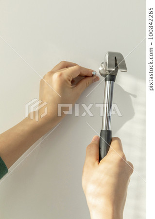 DIY interior hand motion, closeup_hammer a nail into the wa 100842265