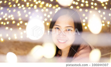 Close-up of the face of the Asian woman among lighting. Close-up of the face of the Asian woman among lighting. 100844307