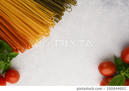 Vegetable spaghetti noodles with cherry tomatoes and basil frame. Pasta ingredients on white stone background with copy space. Top view of Italian food with copy space. Pasta noodles fast food Vegetable spaghetti noodles with cherry tomatoes and basil frame. Pasta ingredients on white stone background with copy space. Top view of Italian food with copy space. Pasta noodles fast food 100844681