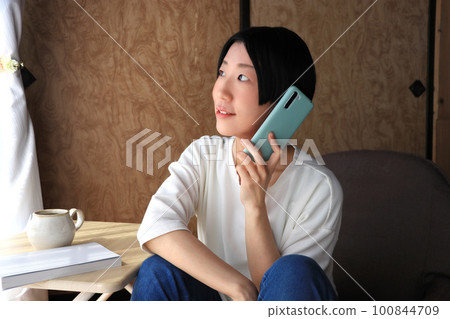 A woman with short black hair talking on a smartphone A woman with short black hair talking on a smartphone 100844709