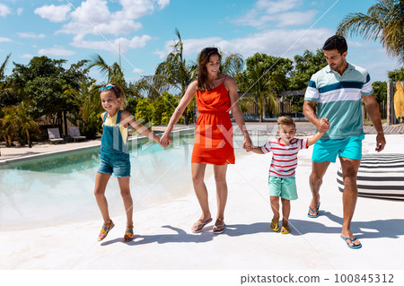 Happy biracial family walking and holding hands by the swimming pool Happy biracial family walking and holding hands by the swimming pool 100845312