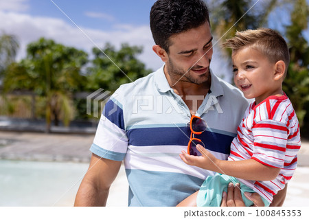 Happy biracial father and son embracing by the swimming pool 100845353