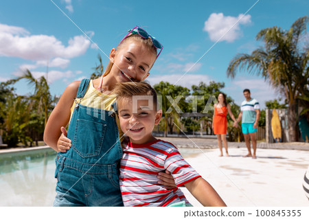 Portrait of happy biracial family taking smiling by the swimming pool Portrait of happy biracial family taking smiling by the swimming pool 100845355