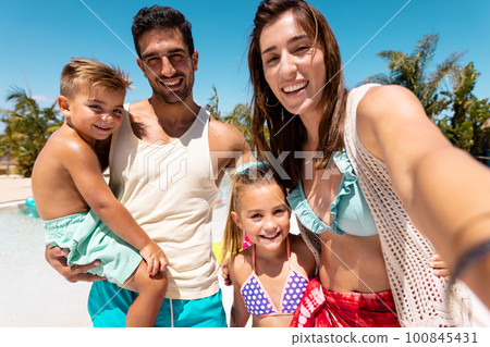Happy biracial family taking selfie by the swimming pool 100845431