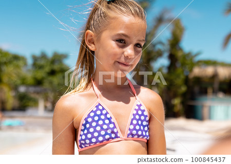 Happy biracial girl smiling by the swimming pool 100845437
