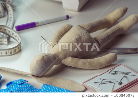 Stuffed rabbit toy with needles lying on table. Knitting hobby and business. Small hare toy next to sewing measure tape Stuffed rabbit toy with needles lying on table. Knitting hobby and business. Small hare toy next to sewing measure tape 100846072