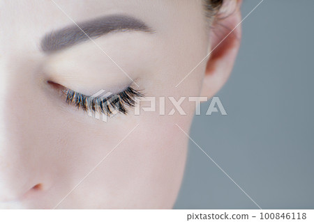 Close-up of closed eye with magnificent long eyelashes, flawless skin, eyebrow of unrecognizable young woman. Macro. 100846118