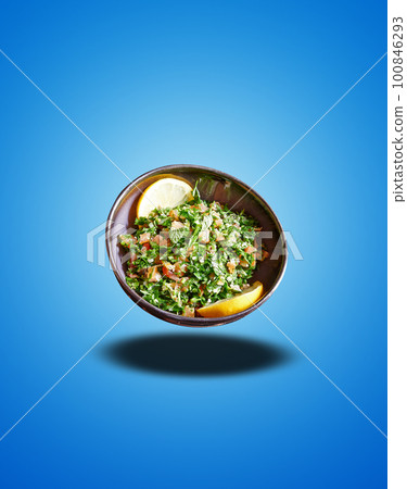 Floating Black bowl with taboule apetizer on blue gradient Floating Black bowl with taboule apetizer on blue gradient 100846293