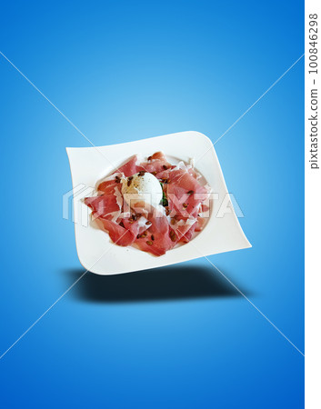 Floating White plate with ham and burata cheese on blue gradient Floating White plate with ham and burata cheese on blue gradient 100846298