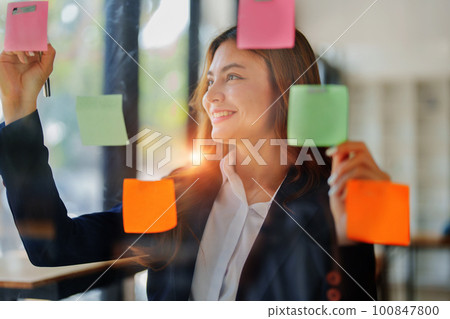 Beautiful young teen asian businesswoman using note pad thinking with planning working on financial document, tax, exchange, accounting and Financial advisor. 100847800