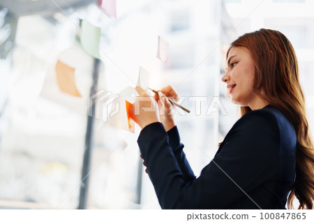 Beautiful young teen asian businesswoman using note pad thinking with planning working on financial document, tax, exchange, accounting and Financial advisor. 100847865