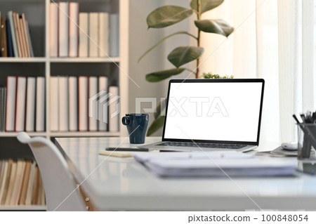 White working desk in modern home office with laptop computer, coffee cup and documents. Blank screen for advertising design 100848054