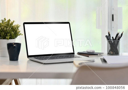 Laptop computer, coffee cup, books and houseplant on white table. Blank screen for your advertising text message 100848056