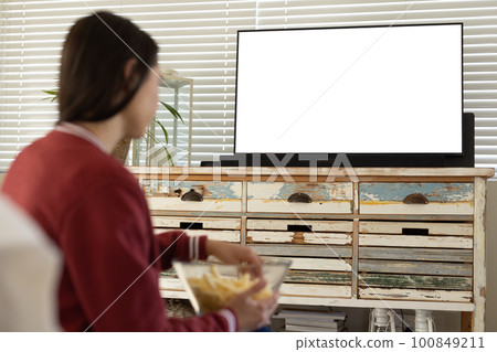 Caucasian young woman having french fries and watching tv while sitting at home, copy space 100849211