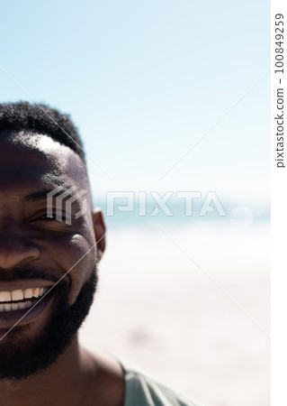 Cropped face of african american mid adult bearded man enjoying at beach against sea and clear sky 100849259