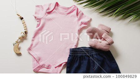 Close up of pink baby gro, booties, denim skirt and toy on white background Close up of pink baby gro, booties, denim skirt and toy on white background 100849829