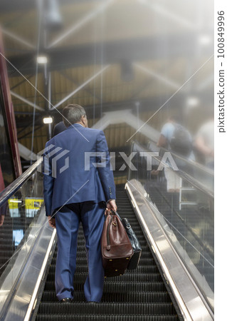 businessman with bags on the escalator at the airport businessman with bags on the escalator at the airport 100849996