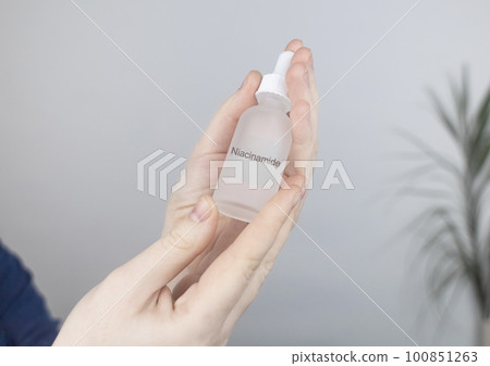 Niacinamide. Girl applies vitamin b3 to her face. Laboratory research. Skincare. Dermatological serum. Emulsion for narrowing of pores, normalization of sebum production and lightening of pigmentation 100851263