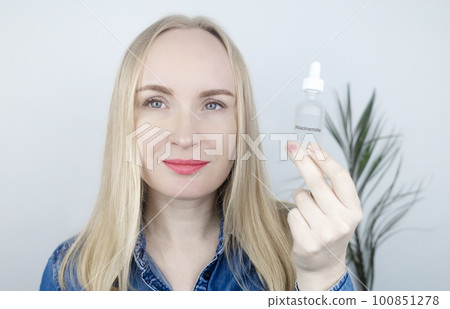 Niacinamide. Girl applies vitamin b3 to her face. Laboratory research. Skincare. Dermatological serum. Emulsion for narrowing of pores, normalization of sebum production and lightening of pigmentation 100851278