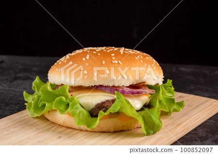 Burger with beef patty on a wooden plate 100852097