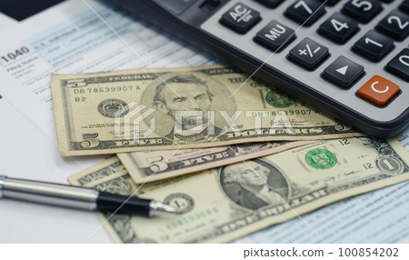 Tax season concept. Tax planning and consulting service business. Pen, calculator, dollar banknote, and income tax return form for filling and calculating tax payments. Money and financial concept. 100854202
