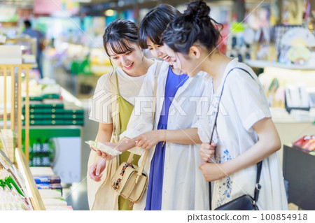 A young woman who enjoys choosing souvenirs on a girls' trip A young woman who enjoys choosing souvenirs on a girls' trip 100854918