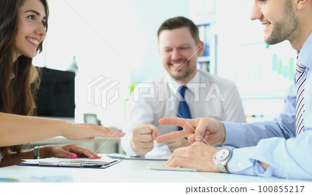 Caucasian businessman and businesswoman playing Rock Paper Scissors with business people 100855217