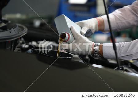 Closeup of experienced mechanic checking and pouring oil into special hole in car Closeup of experienced mechanic checking and pouring oil into special hole in car 100855240