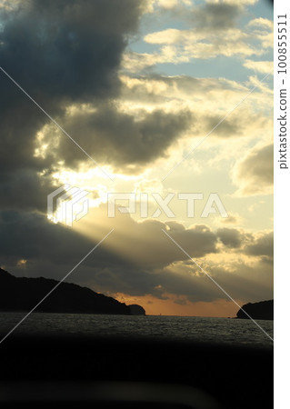 The sun peeking through the clouds, the sun setting over the sea 100855511