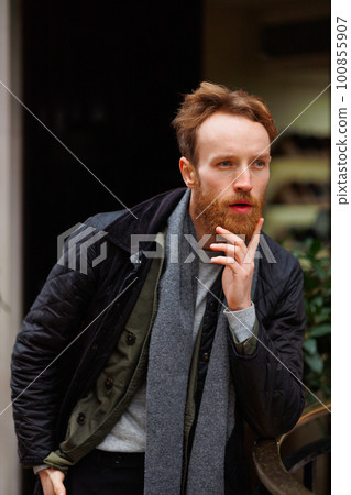 Thoughtful man posing outdoors leaning against the railing 100855907