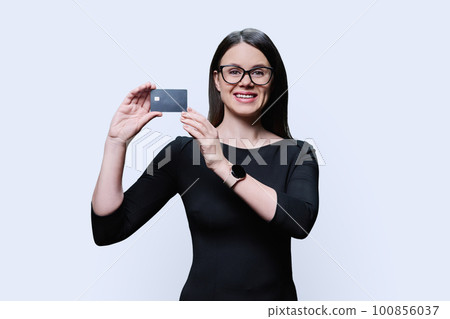 Young woman holding credit card in her hands on white background 100856037