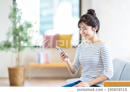 Young woman looking at her smartphone in the living room 100859518
