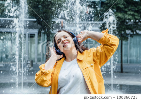 Outdoor portrait of Woman in headset in sound healing therapy. Healing Sounds and Sound Therapy. Sound vibrations for opening, clear, and balance chakras and energy. 100860725