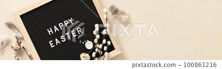 Easter composition with letter board, easter eggs, feathers and spring branches on beige background Easter composition with letter board, easter eggs, feathers and spring branches on beige background 100861216