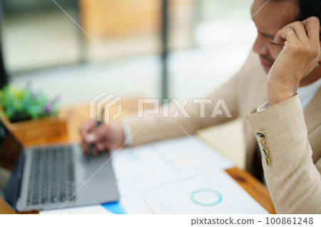 Portrait of sme business owner, man using computer and financial statements Anxious expression on expanding the market to increase the ability to invest in business. 100861248