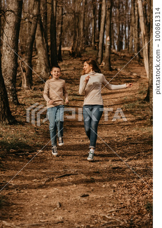 Happy Mother and Child Running on Path in Forest Happy Mother and Child Running on Path in Forest 100861314