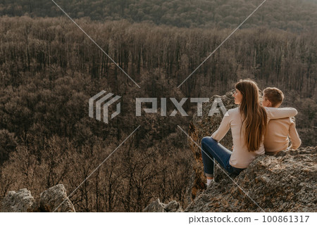 Mother and Child Sitting on Forest Rock after Hiking 100861317