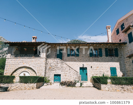 Inner courtyard of an old stone house with green shutters on the windows Inner courtyard of an old stone house with green shutters on the windows 100861379