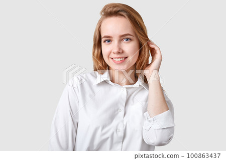 Photo of pleasant looking woman with toothy smile, blue eyes, healthy skin, has nice hairstyle, dressed in elegant formal shirt, ready for meeting, isolated over white background, has natural beauty Photo of pleasant looking woman with toothy smile, blue eyes, healthy skin, has nice hairstyle, dressed in elegant formal shirt, ready for meeting, isolated over white background, has natural beauty 100863437