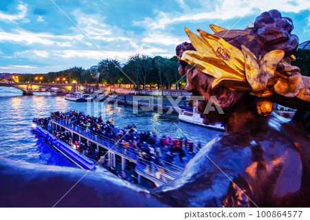 Pleasure boat quickly moving on Seine river - illuminated in twilights on Pont Alexander 3 Pleasure boat quickly moving on Seine river - illuminated in twilights on Pont Alexander 3 100864577