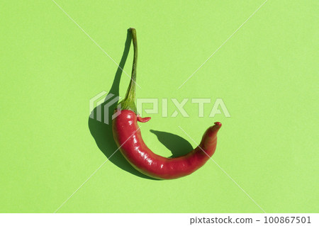 red hot pepper on a green background with a hard shadow red hot pepper on a green background with a hard shadow 100867501