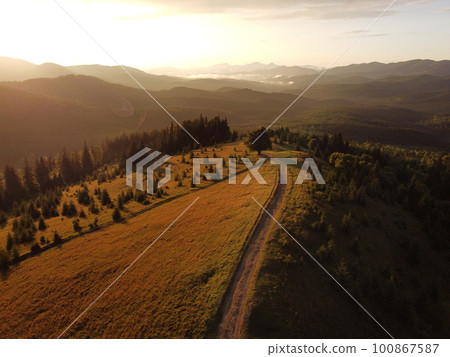 Aerial view of beautiful mountain Carpathians, Ukraine in sunlight. Drone filmed an landscape with coniferous and beech forests, around a winding serpentine road, copter aerial photo 100867587