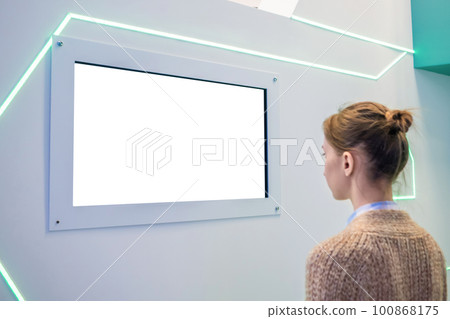 Woman looking at blank white display wall at exhibition - white screen concept Woman looking at blank white display wall at exhibition - white screen concept 100868175
