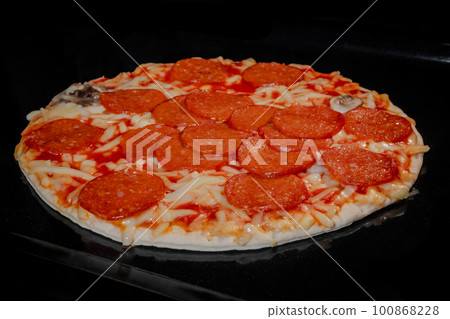 Homemade pizza baking on tray in electric oven, black background Homemade pizza baking on tray in electric oven, black background 100868228