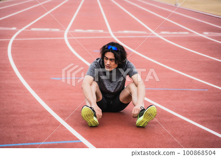 坐在田徑跑道上的男賽跑者 100868504