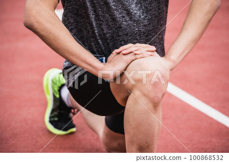 Runners stretching on athletics track 100868532