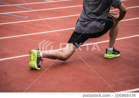 Runners stretching on athletics track 100868536