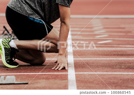 Runners at the starting line on the track of an athletics stadium Runners at the starting line on the track of an athletics stadium 100868545