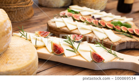 Delicious yummy cheese mix with figs on wooden board in restaurant. Tasting, degustation. 100869534